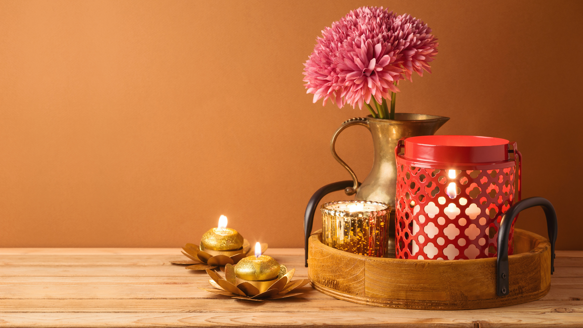 Decorative setup with candles and a vase of pink flowers on a wooden surface diwali gift hamper boxes